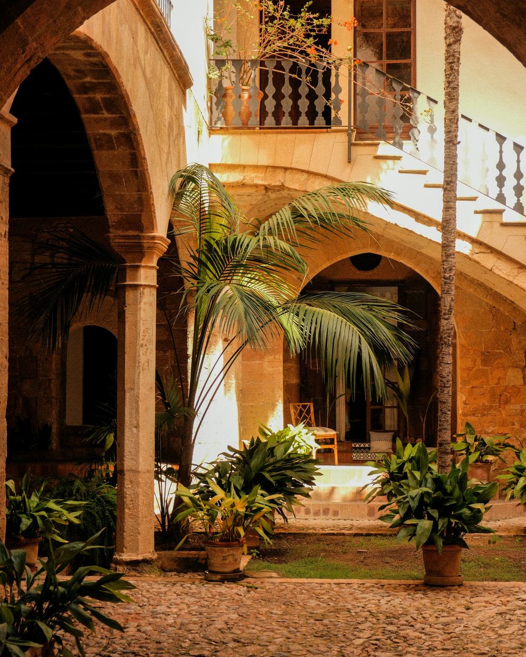 Lichtdurchfluteter Innenhof mit Steinbögen und Palmen in Palma